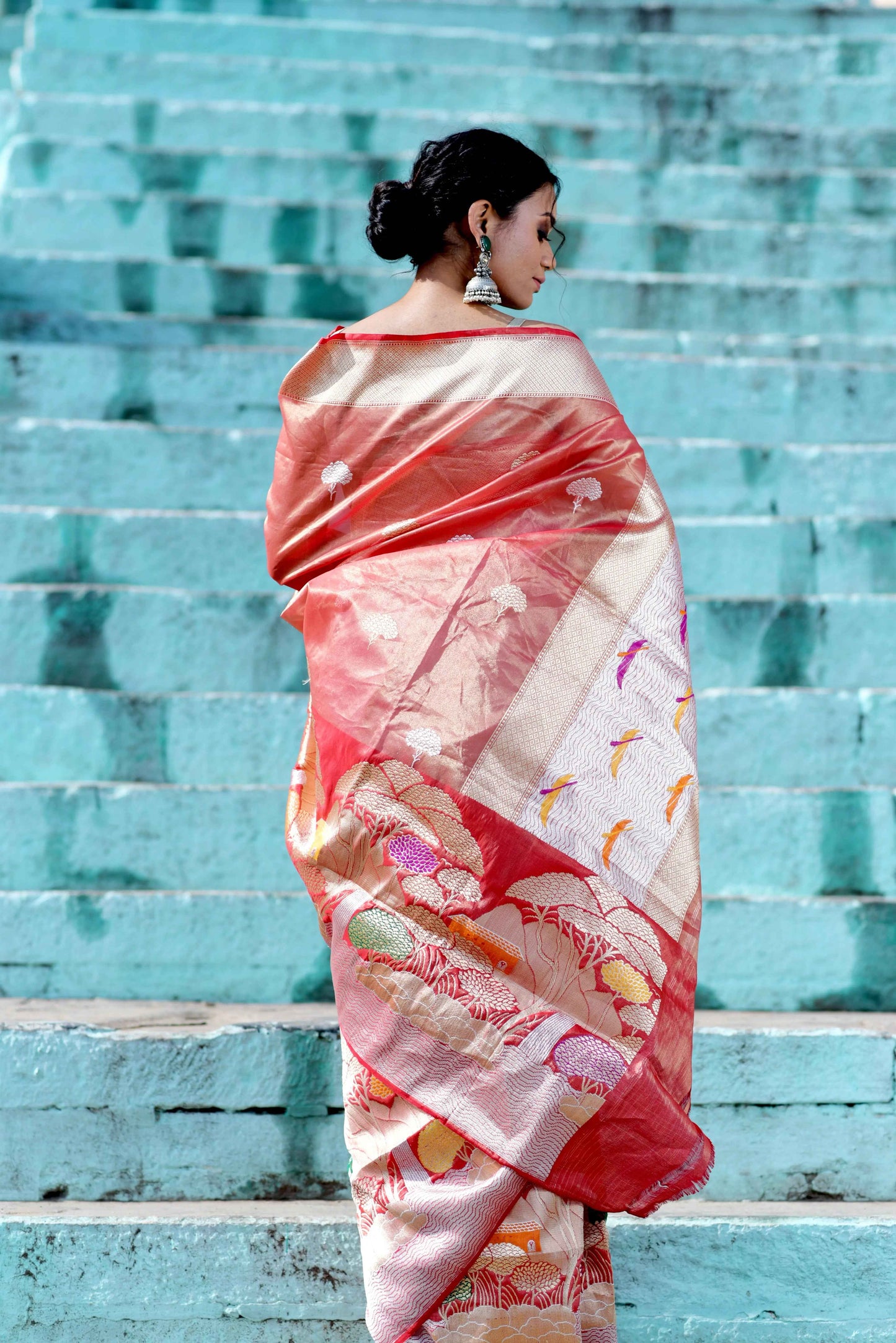 Coral pink saree with wide pallu, light border, and woven motif details