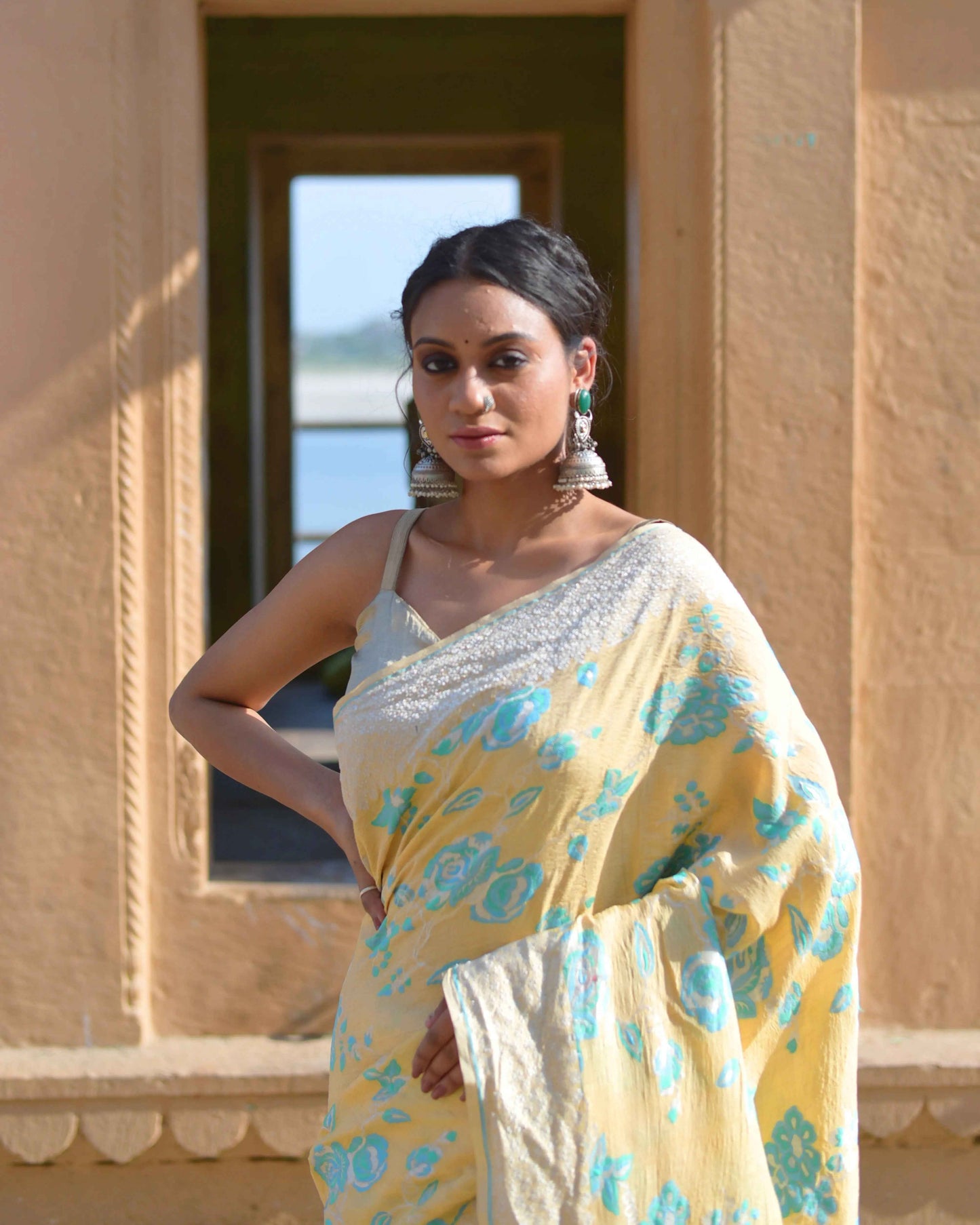 Banaras handloom saree with cream base and turquoise floral motifs, draped