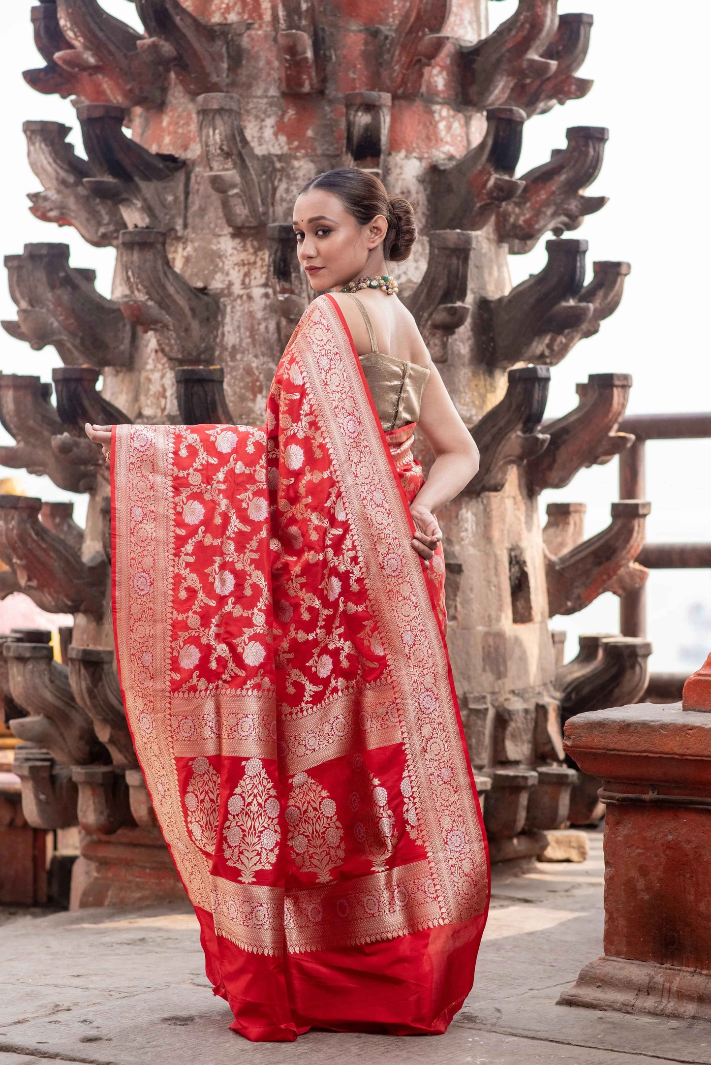 Red saree draped with wide cream-gold border and floral pattern details