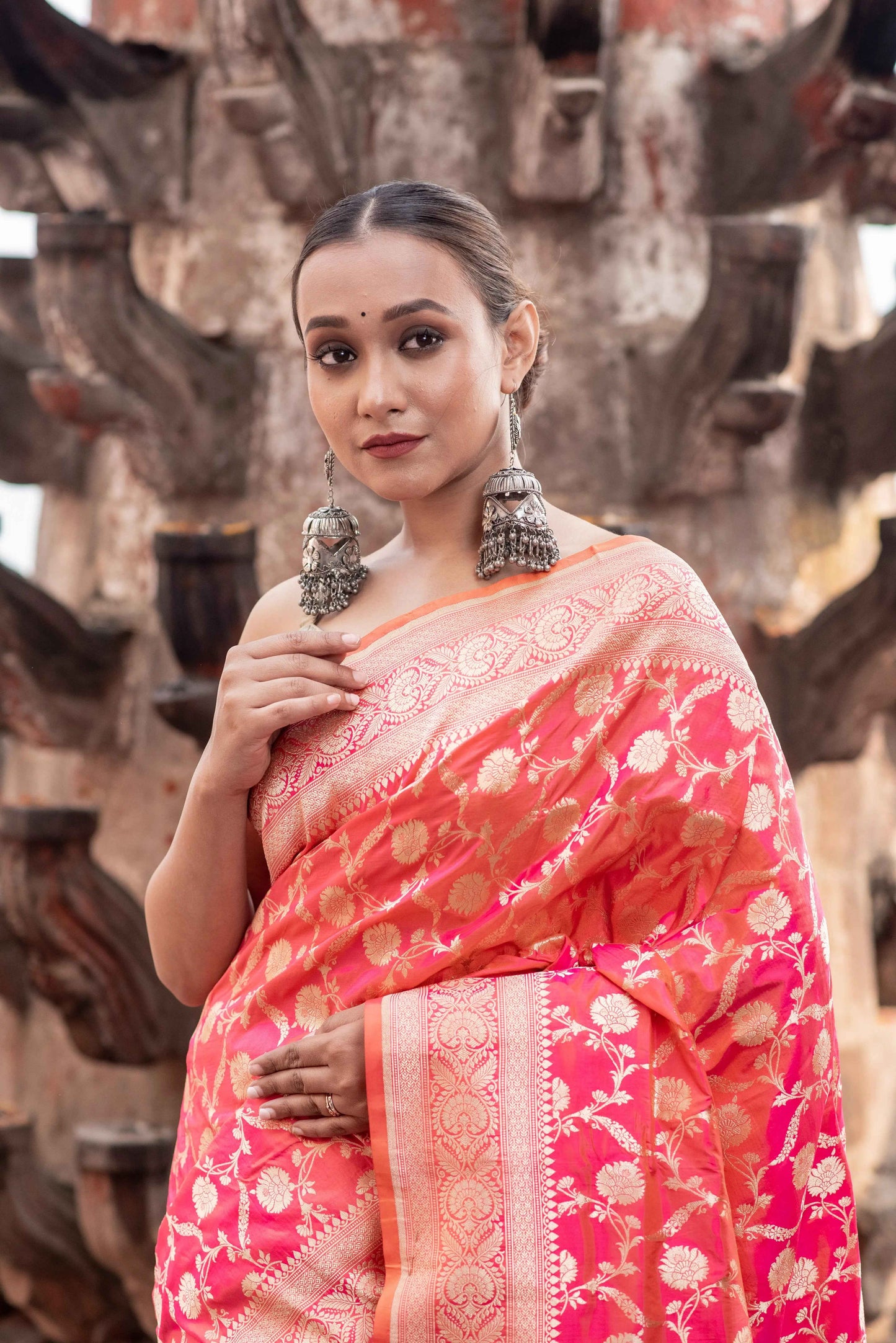 Coral pink handloom saree with woven gold border and floral motifs, pallu draped