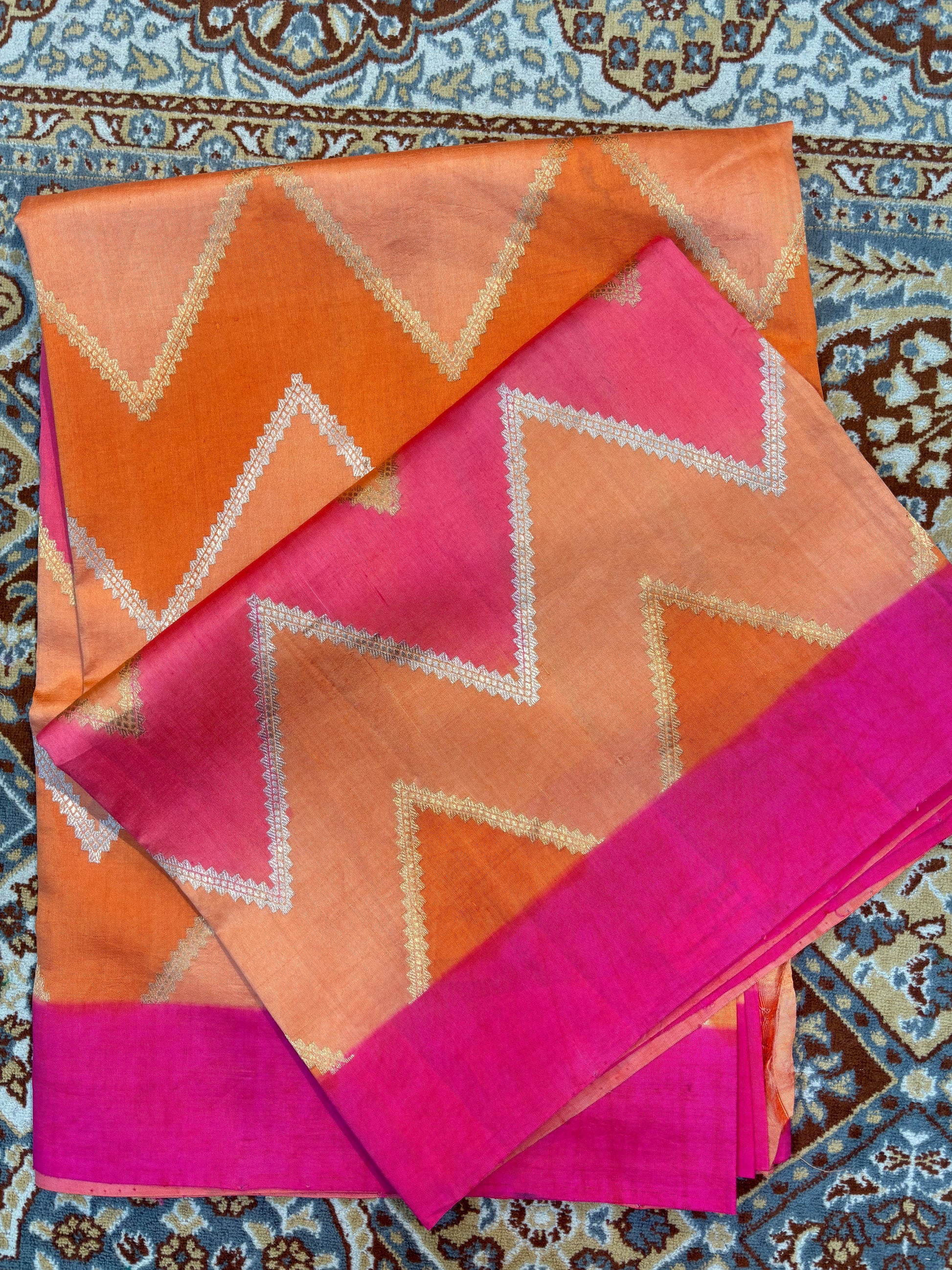 Orange-pink saree with white zigzag pattern and wide magenta border
