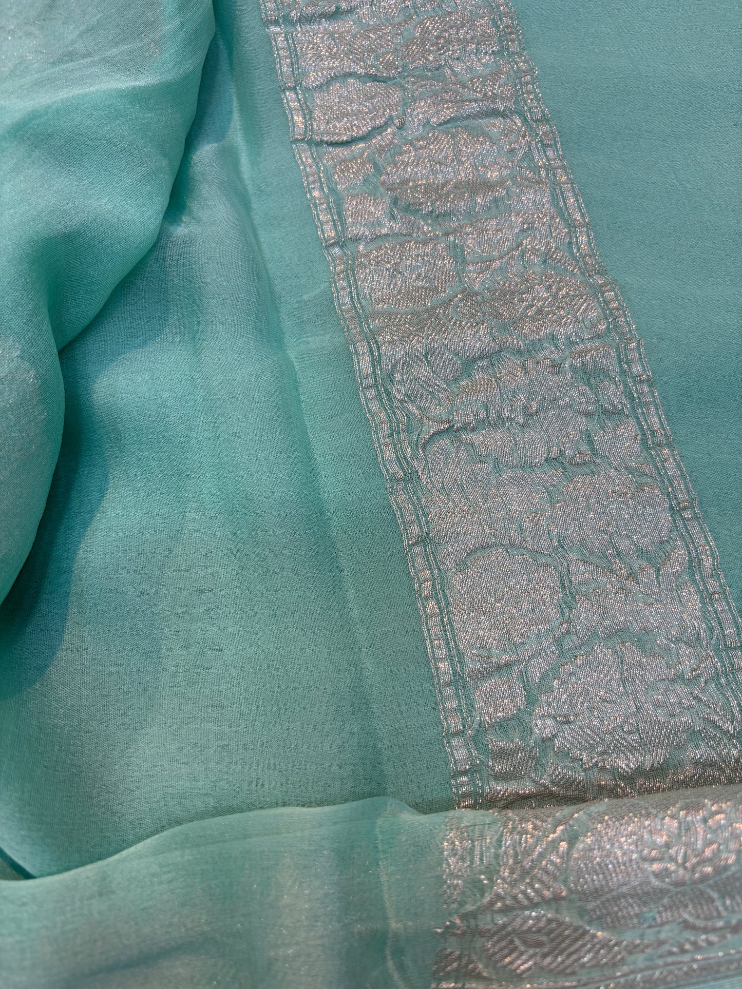 Teal chiffon saree with textured silver border panel and decorative edge trim