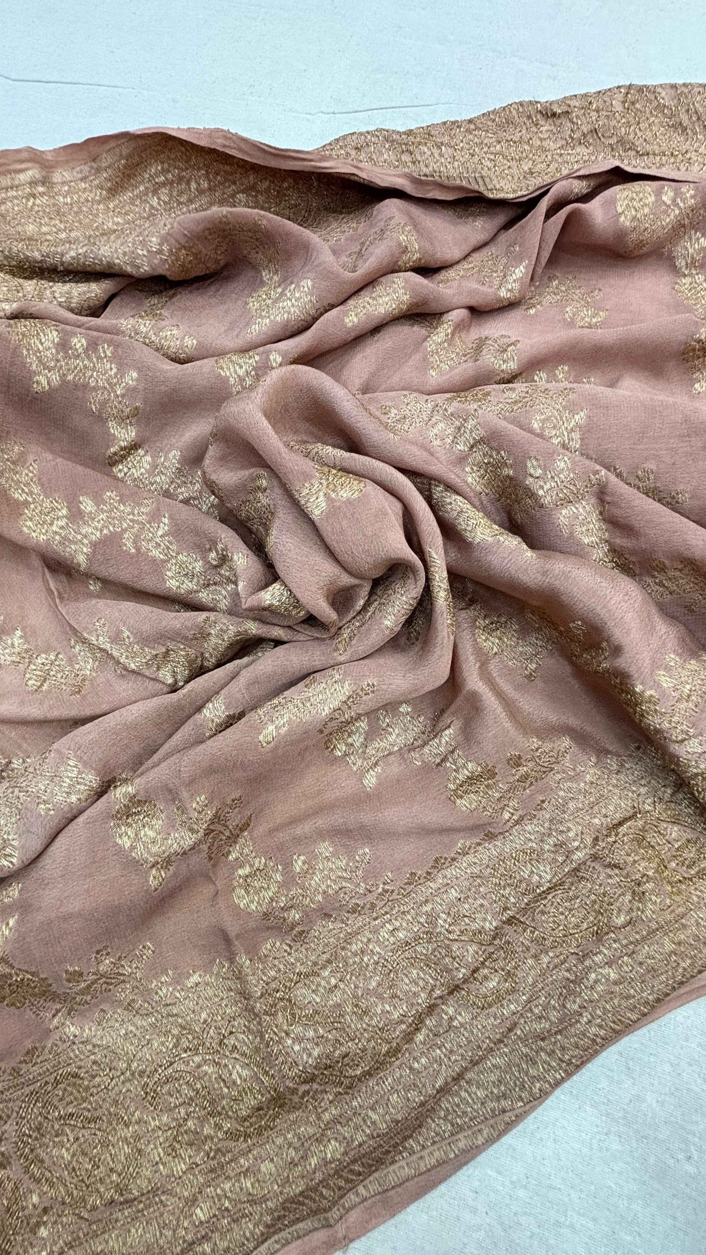 Dusty pink saree fabric with gold zari motifs, softly crinkled texture