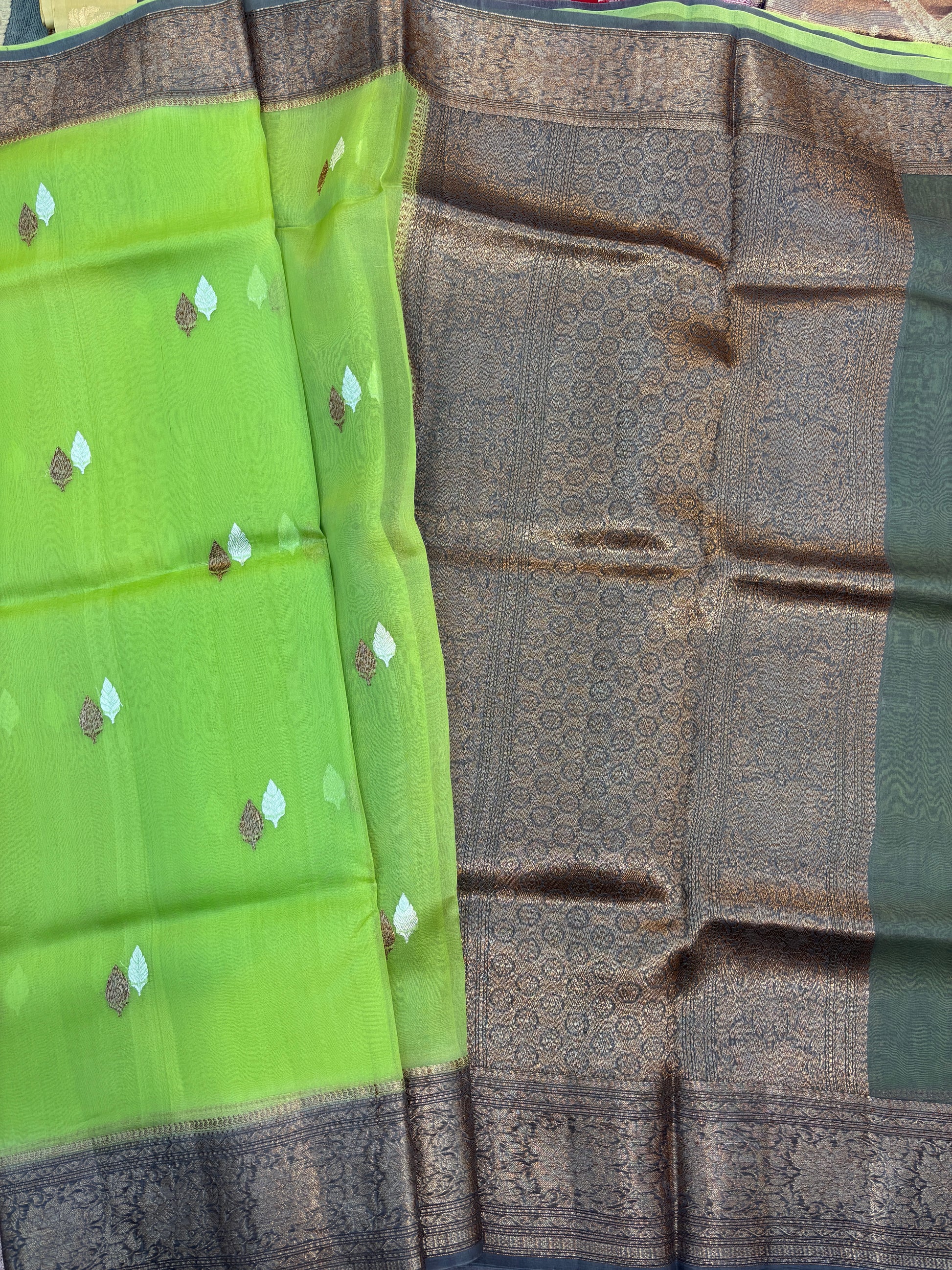 Green and charcoal silk saree with leaf-like gold motifs and woven border