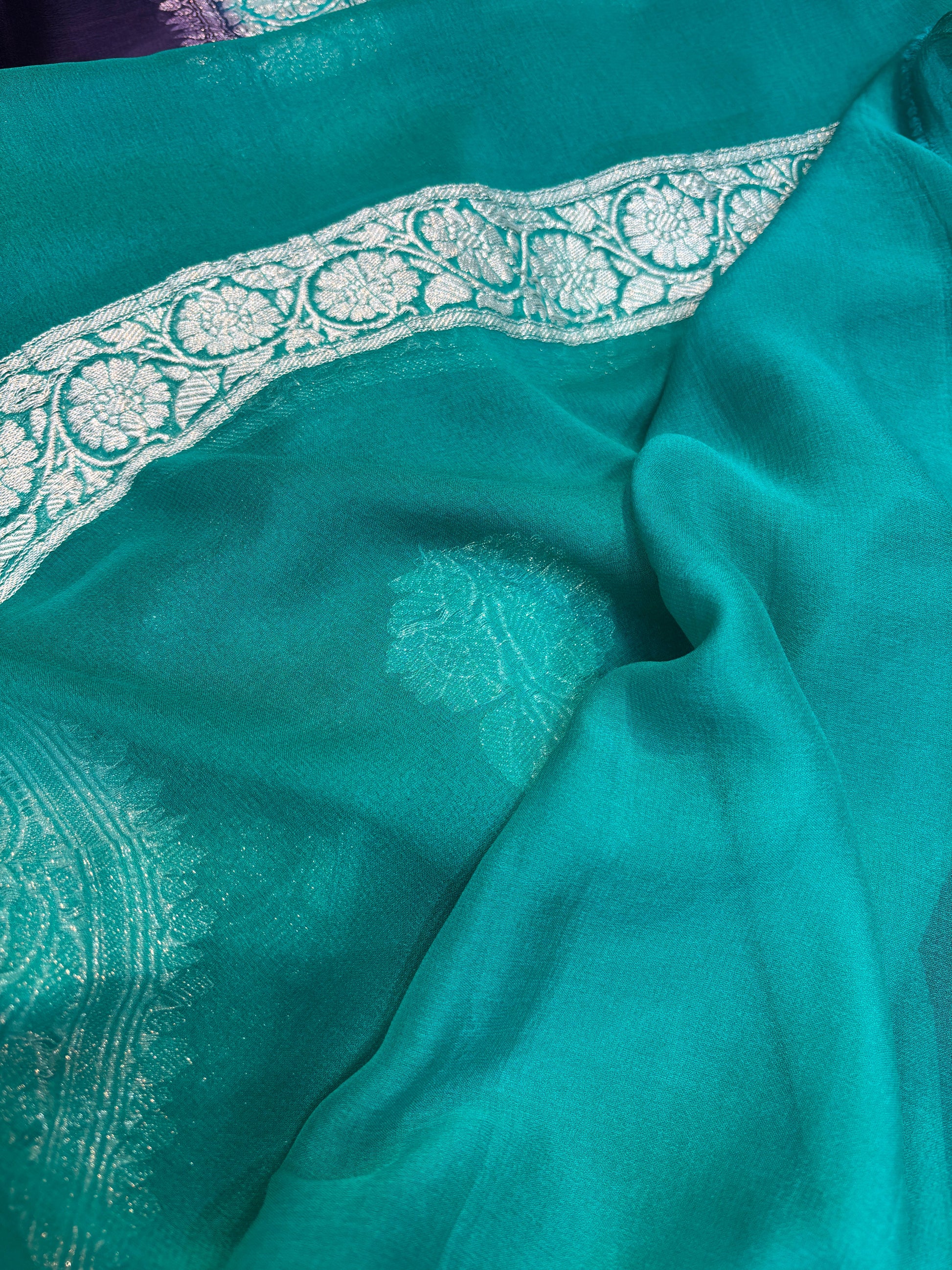 Teal chiffon saree with ornate silver border and shimmering leaf motifs