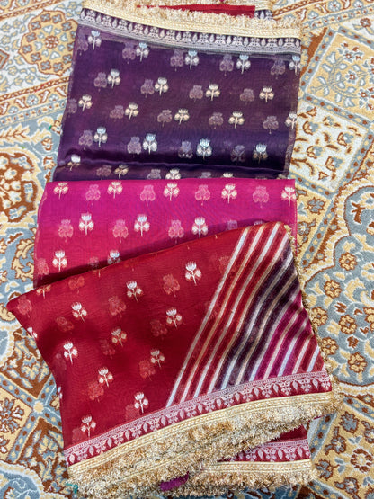 Folded saree pieces with purple and maroon motifs, striped panel, and gold border