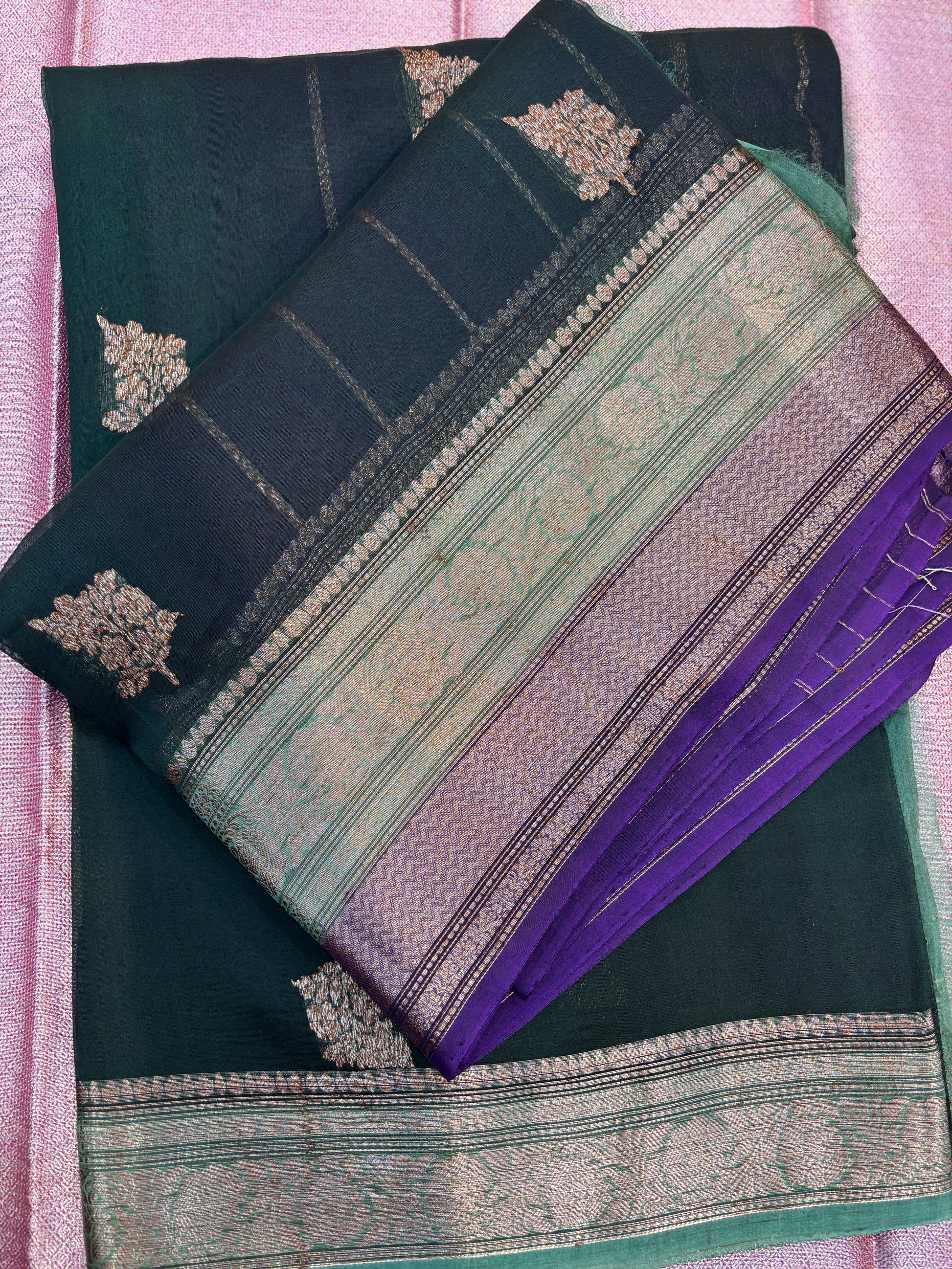 Folded teal and purple handloom saree with gold motifs and striped zari border