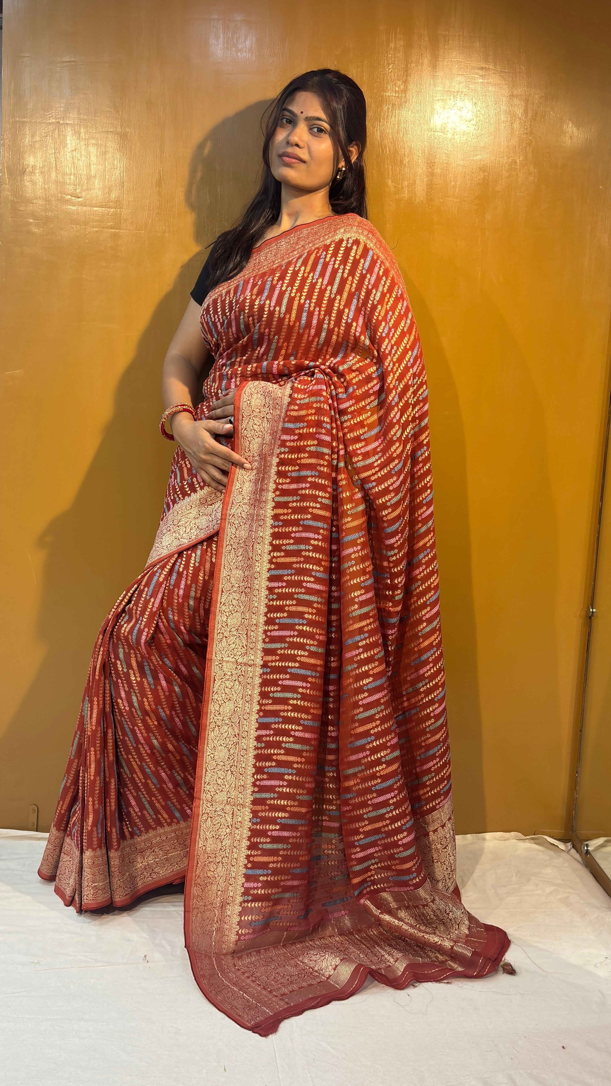 Pink saree with gold-toned allover pattern and cream-gold border, full drape view