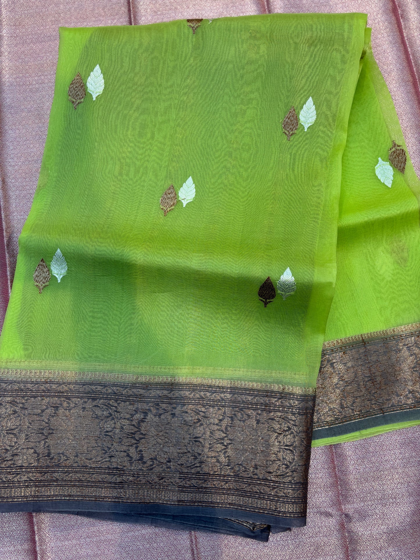 Bright green silk saree with scattered leaf motifs and dark jacquard border