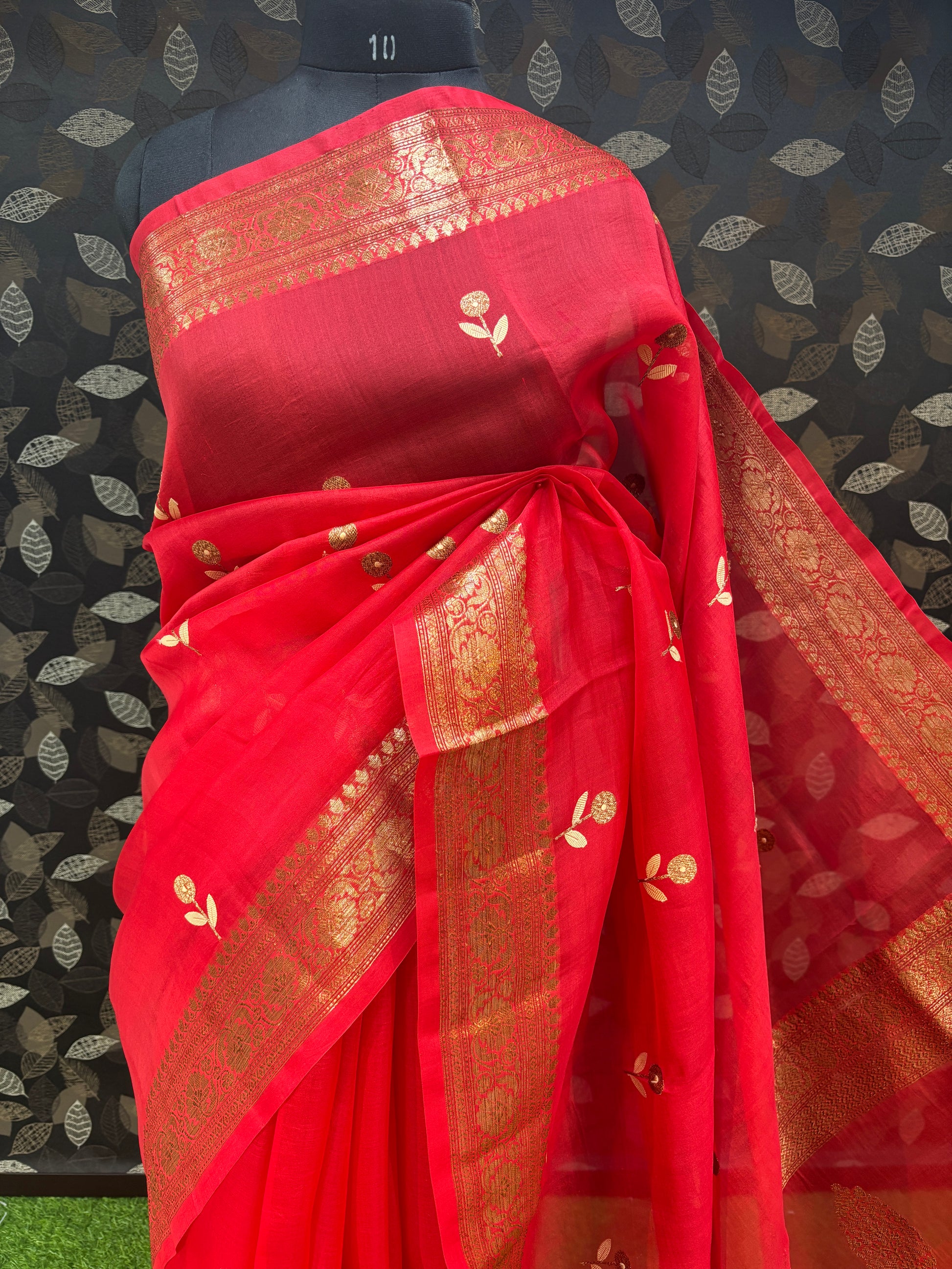 Red silk sari with gold woven pallu border and small motifs, folded presentation