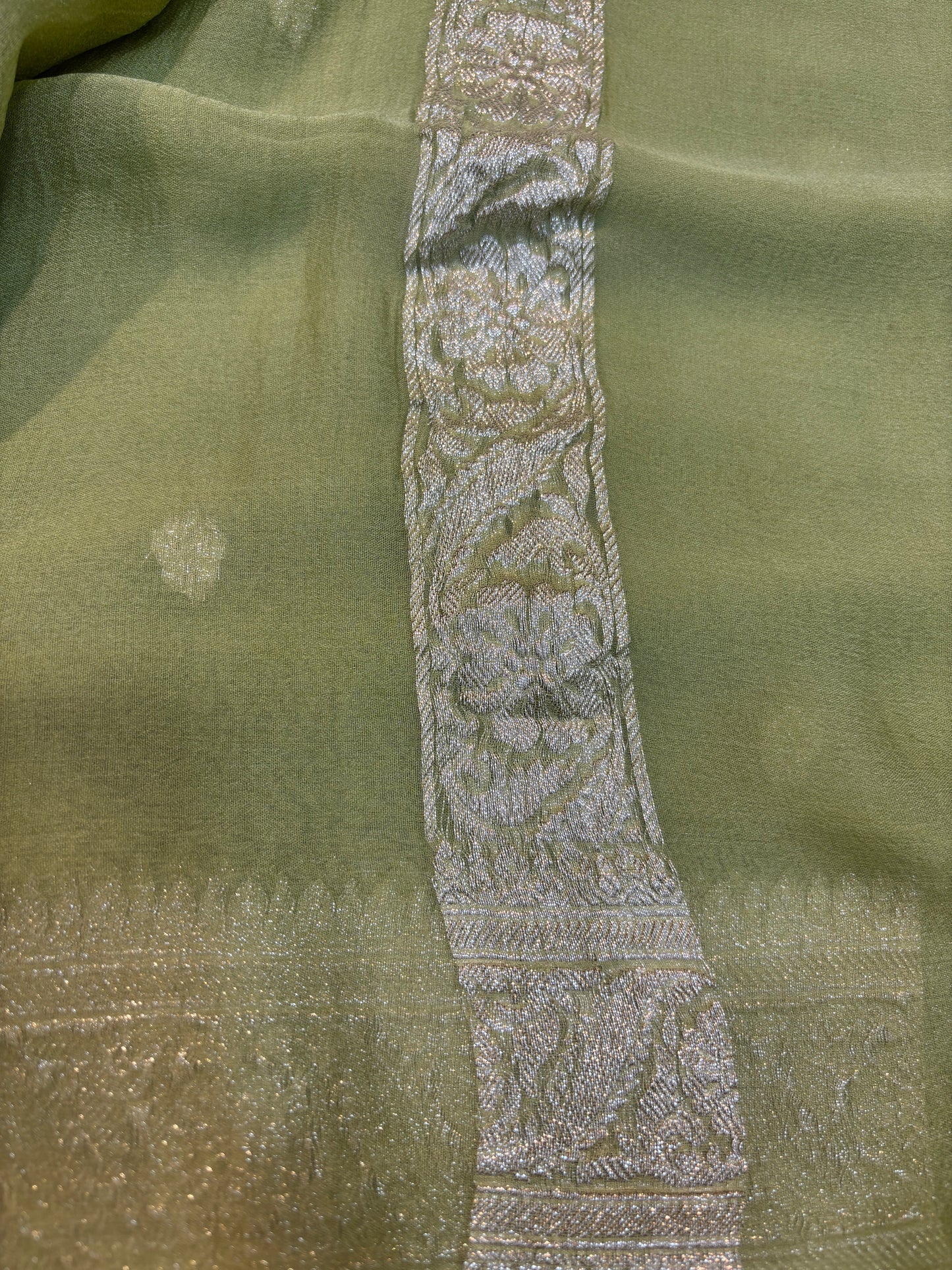 Sage green Banarasi handloom saree with silver-tone embroidered border panel detail.
