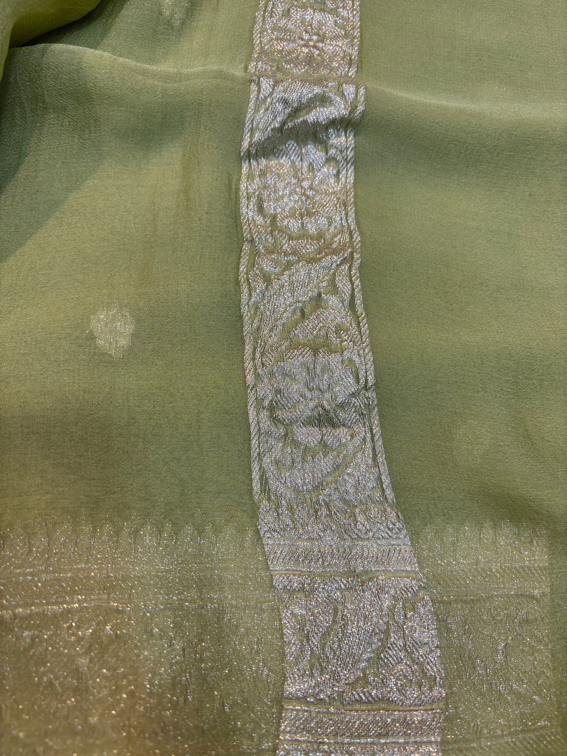 Sage green Banarasi handloom saree with silver-tone embroidered border panel detail.