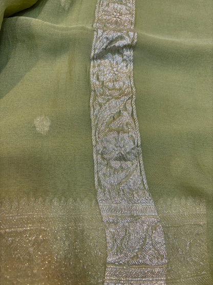 Sage green Banarasi handloom saree with silver-tone embroidered border panel detail.