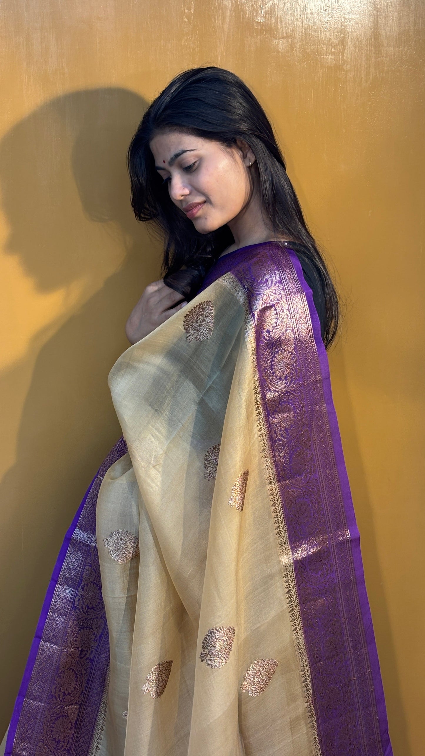 Cream saree with purple zari border and gold motif pallu, draped