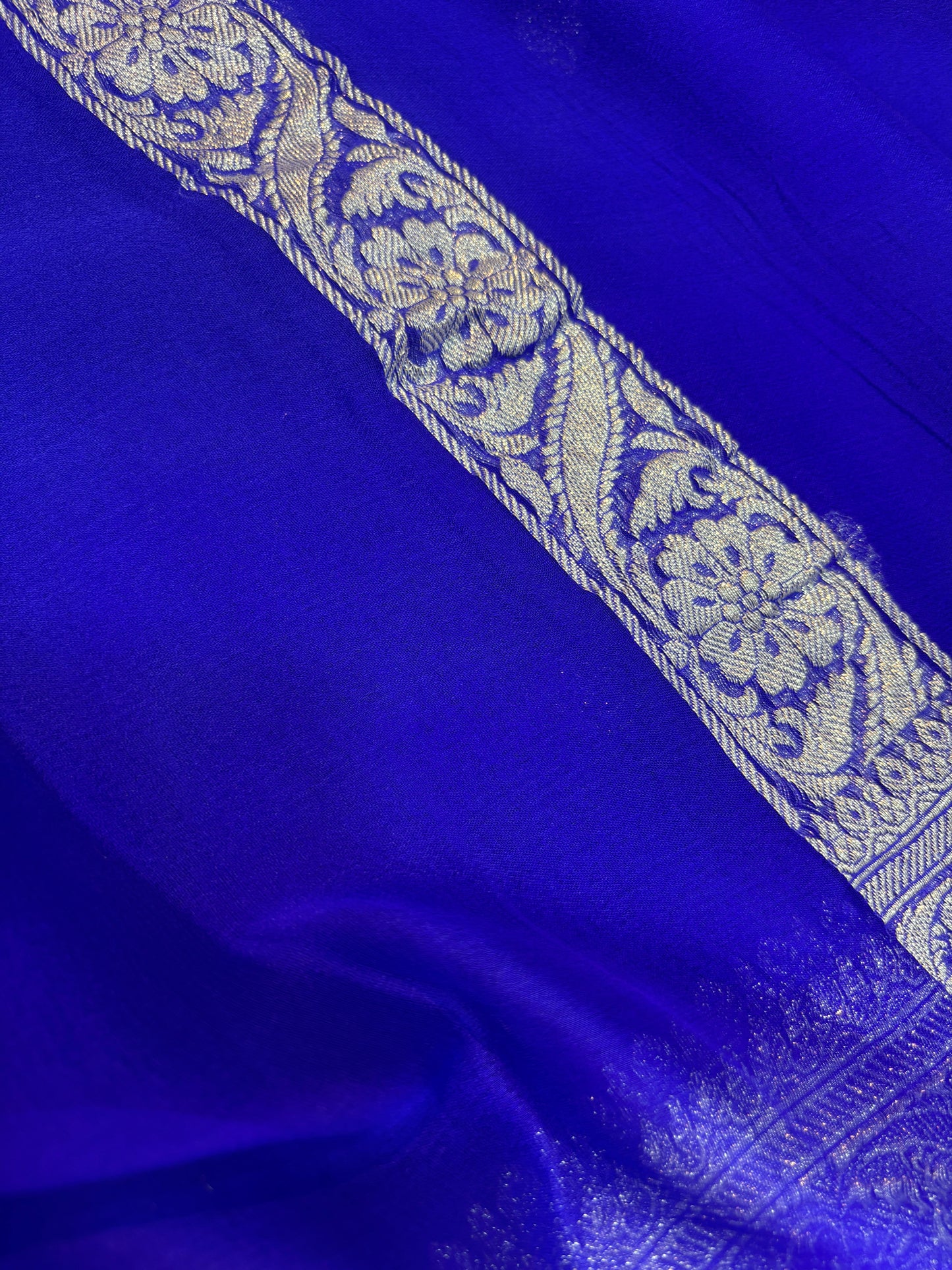 Royal blue Banarasi handloom saree with silver-tone ornate border and floral panel detail.
