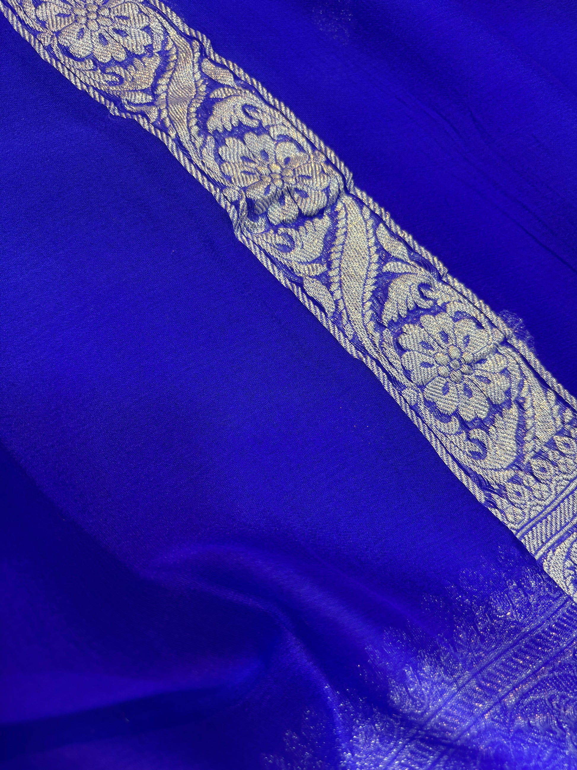 Royal blue Banarasi handloom saree with silver-tone ornate border and floral panel detail.