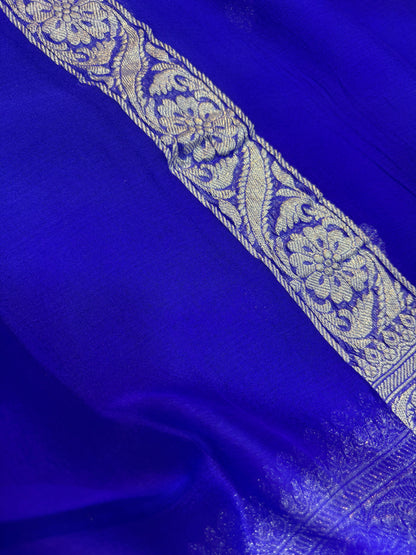 Royal blue Banarasi handloom saree with silver-tone ornate border and floral panel detail.