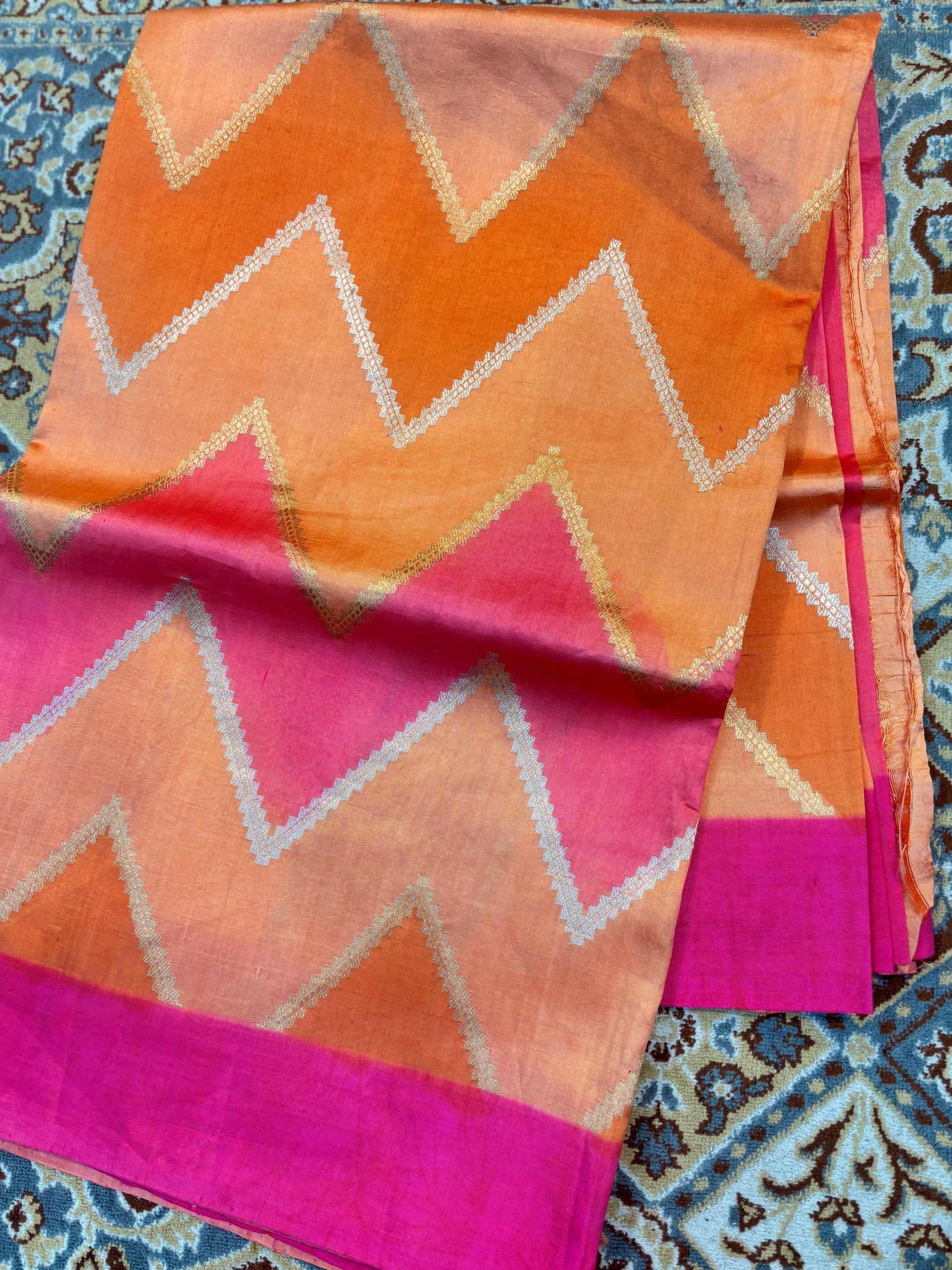 Orange saree with zigzag chevrons, magenta pallu, and gold border