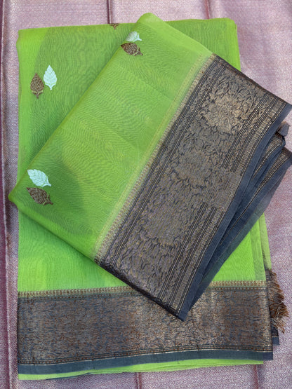 Folded green silk saree with leaf motifs and dark patterned zari-style border