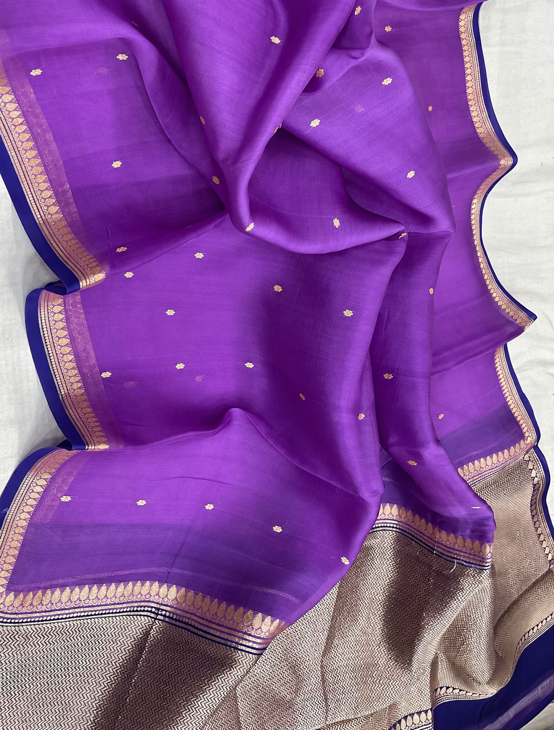 Purple silk saree with gold dot motifs and woven zari border, draped fabric close-up