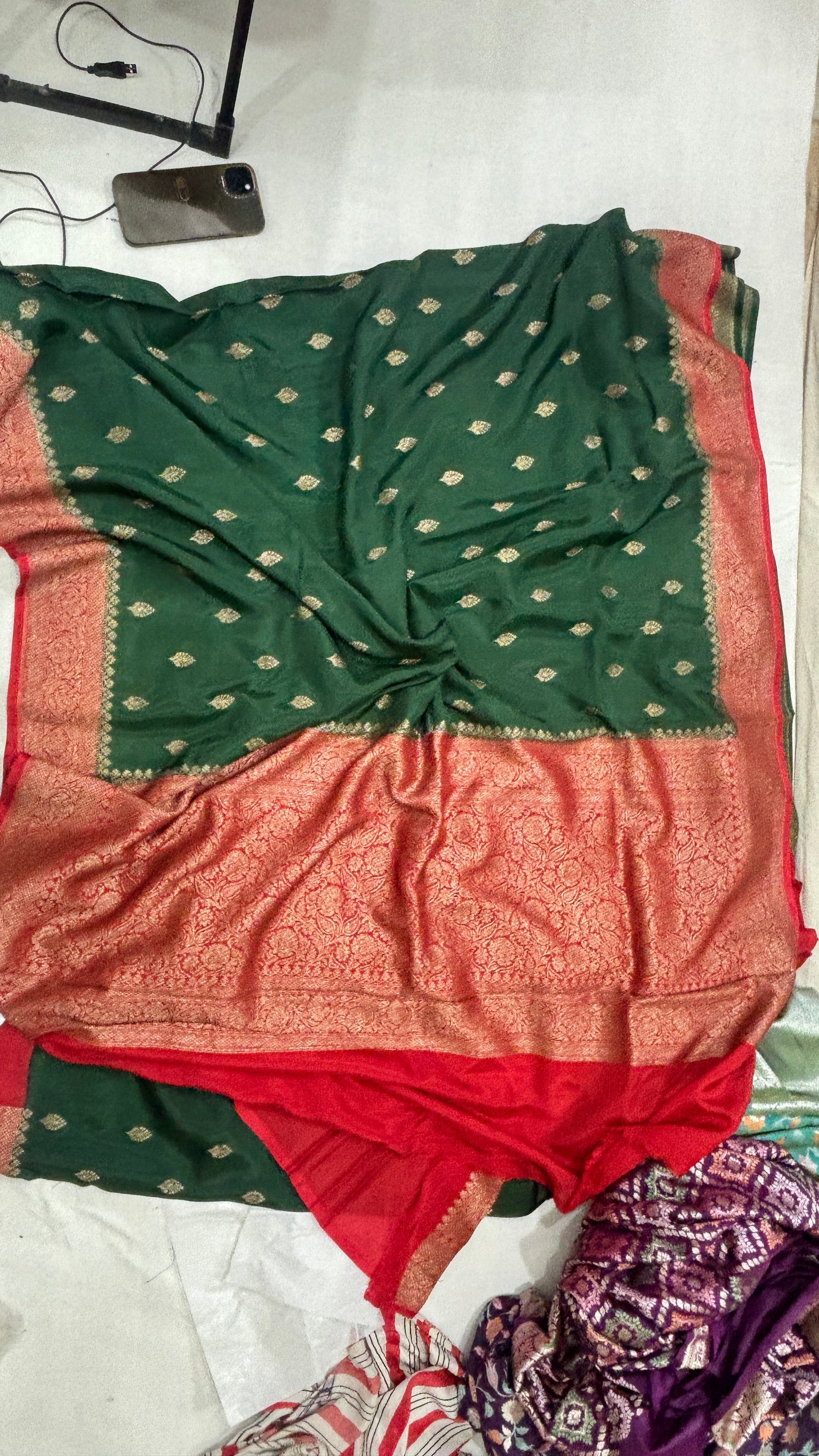 Folded green saree with red and gold border, gold motif dots