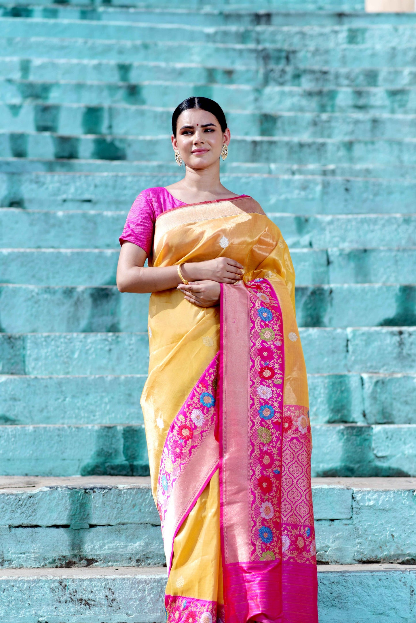 Yellow saree with magenta border, pink patterned endpiece, and draped pleats
