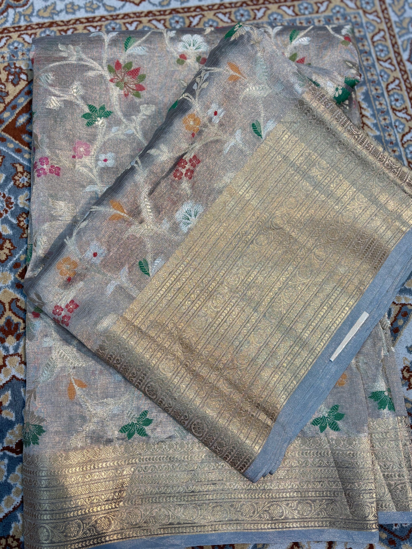 Folded handloom saree with silver-gray floral pattern and gold-toned woven border