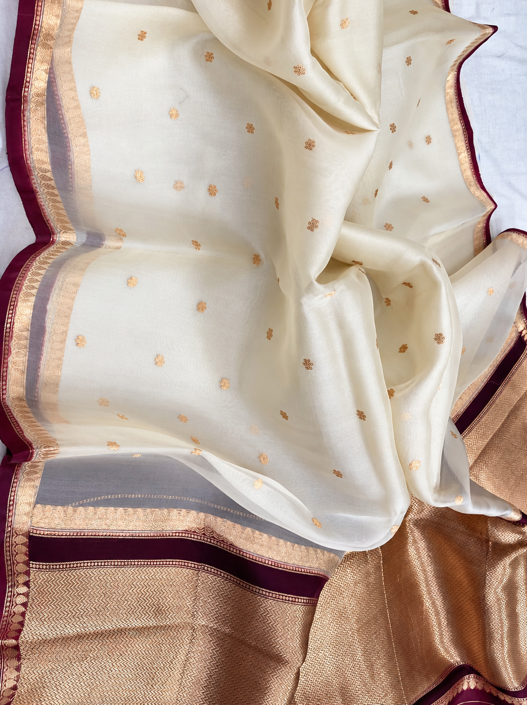 Draped ivory silk saree with scattered gold motifs and maroon-gold pallu border