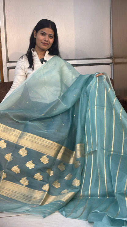 Ice-blue silk Banarasi sari with gold striped border and draped pallu, side view