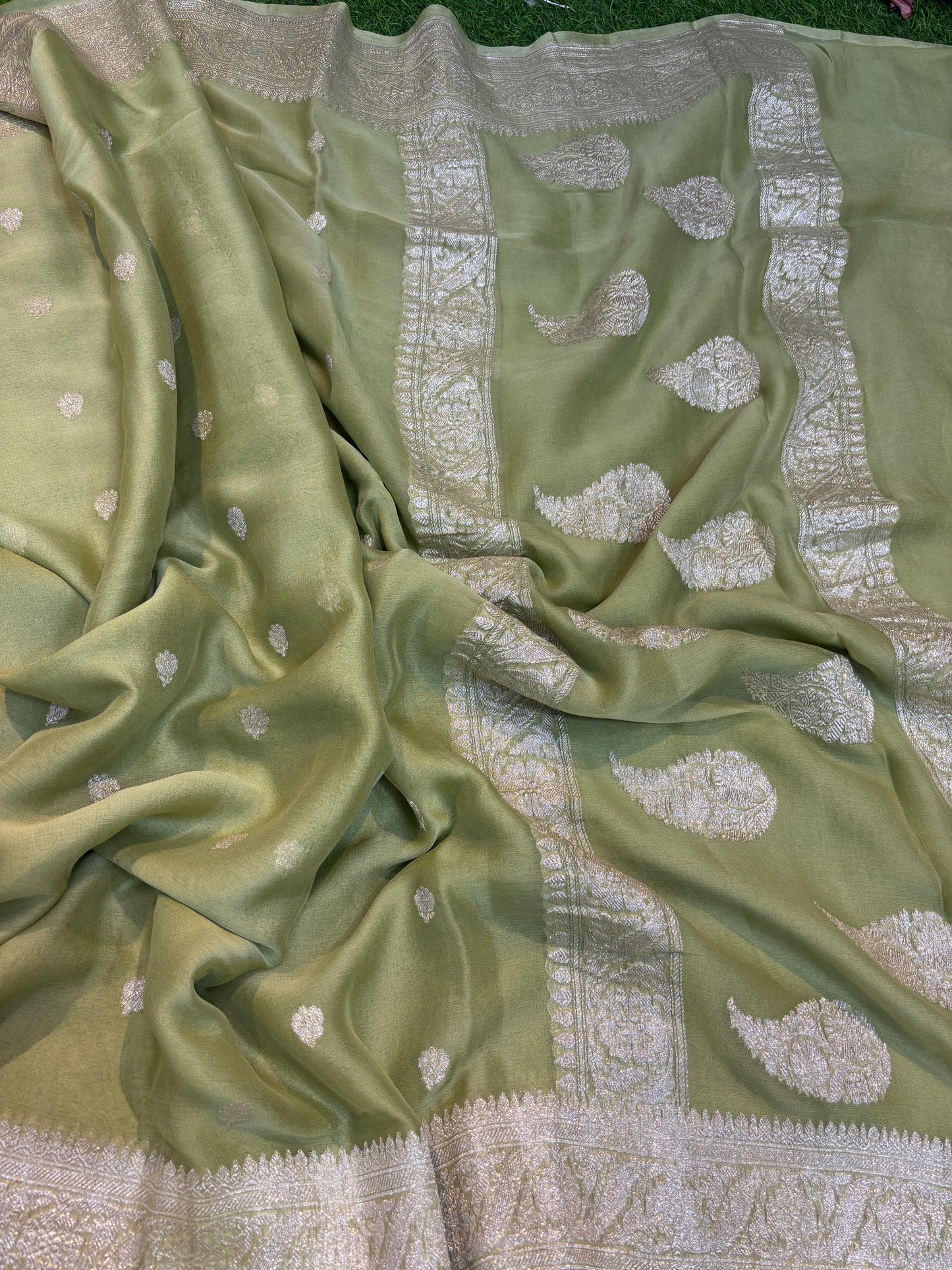 Pale green Banarasi handloom saree with silver-tone leaf motifs and patterned border.