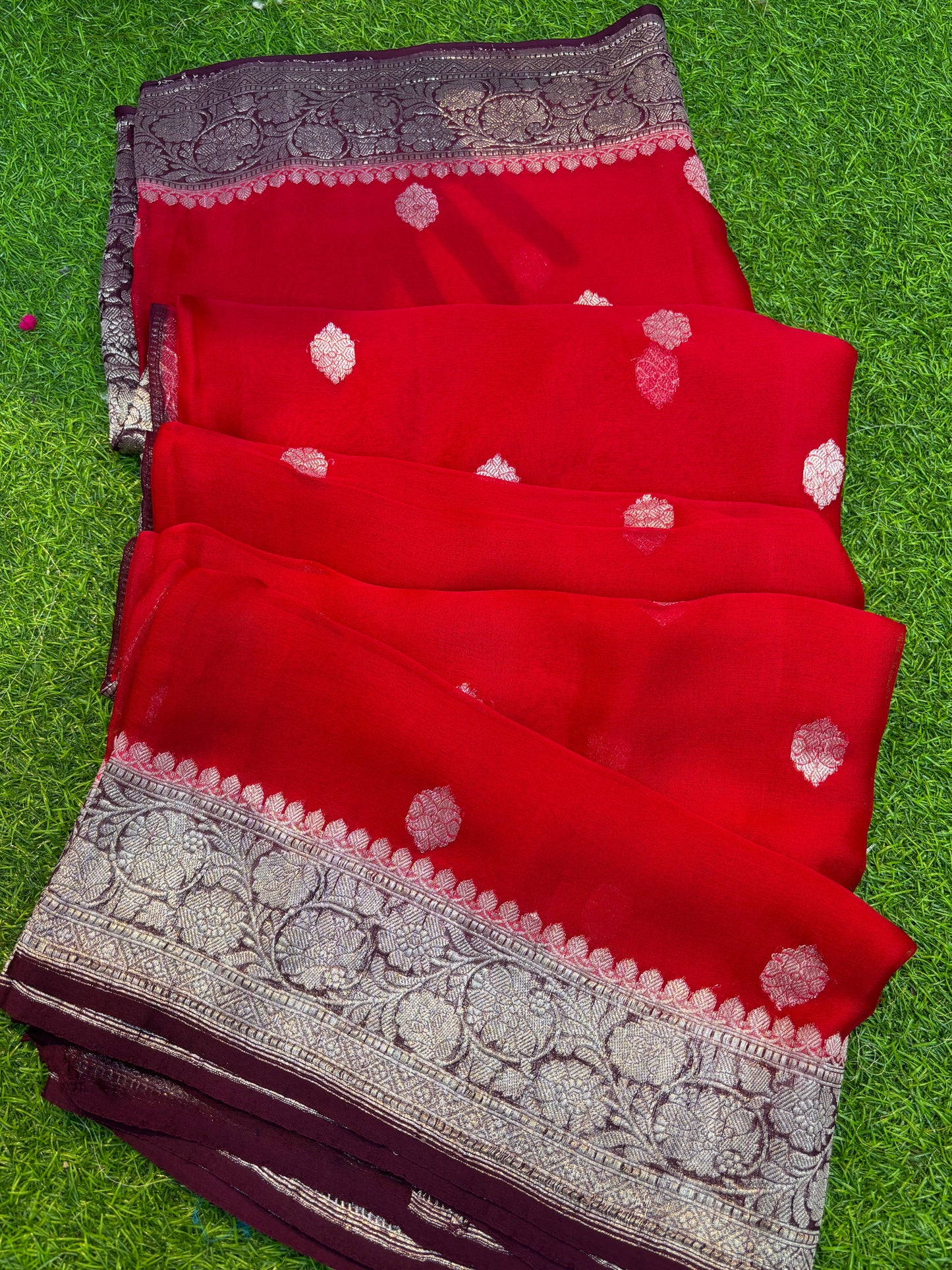 Red Banarasi handloom saree with silver-tone motif pattern and woven border band.