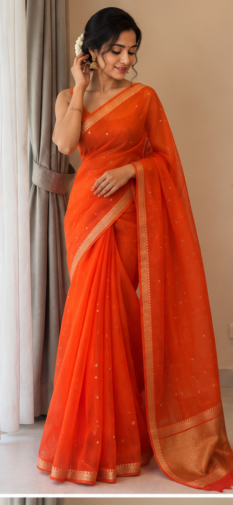 Orange silk saree with gold zari border and dotted motifs, model adjusting drape